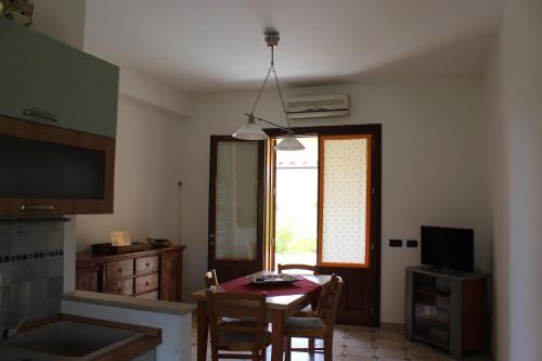 a kitchen with a table and a dining room at Casa Vacanze Libeccio - Villetta con giardino e piscina condominiale in Custonaci