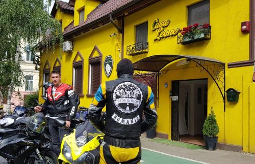 a man standing in front of a yellow building with motorcycles at Pension Casa Leone in Timişoara