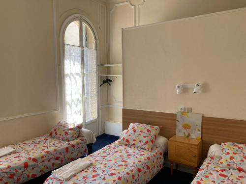 une chambre avec deux lits et une fenêtre dans l'établissement Hôtel Belle Meunière, à Nice