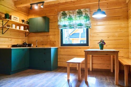 una cocina con armarios verdes, una mesa y una ventana en Polana Świerkowa, en Okuninka
