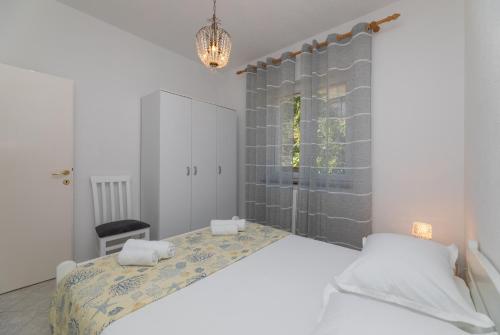 a bedroom with a large bed and a chandelier at Apartments Ella in Supetar