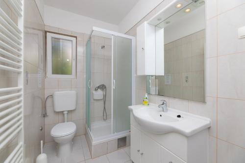 a bathroom with a toilet and a sink and a shower at Apartments Ella in Supetar