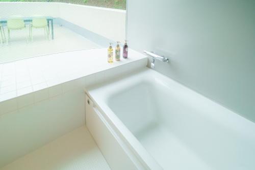 a white bathroom with a tub and a sink at TAKAONE ACTIVITY＆STAY in Hachioji