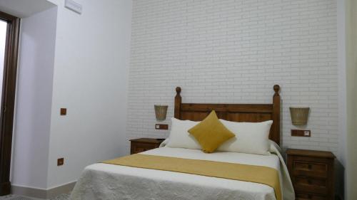 a bedroom with a bed with white and yellow pillows at LA CASONA DE MANUELA in San Benito de la Contienda