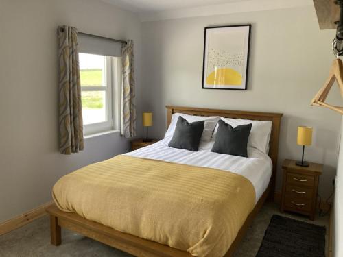 a bedroom with a large bed and a window at Derrie Farm Cottage in Newton Stewart