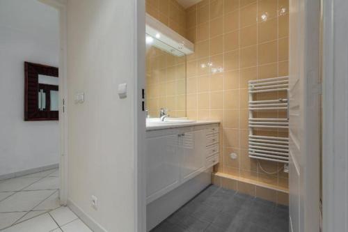 La salle de bains est pourvue d'un lavabo blanc et d'une baignoire. dans l'établissement Cannes centre 2mins from beach stunning 3-Bed Apt, à Cannes