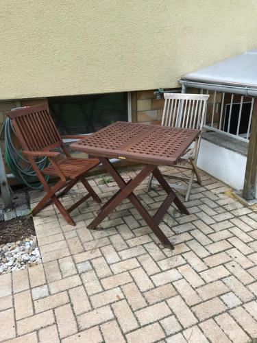 a wooden picnic table and two chairs on a patio at Helles Doppelzimmer im Untergeschoss mit Bad im Grünen nahe Potsdam in Michendorf