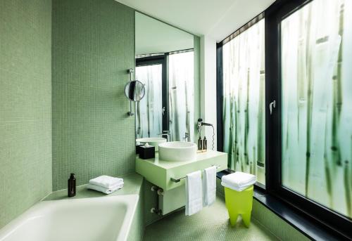 a bathroom with a tub, sink and mirror at Art Hotel City Leipzig in Leipzig