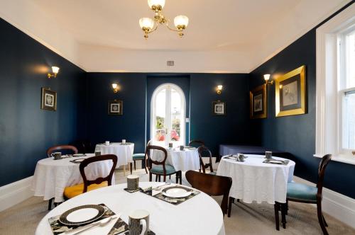 um restaurante com mesas e cadeiras brancas e uma janela em Windarra on High em Launceston