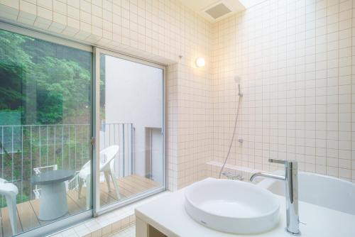baño con bañera, lavabo y ventana en TAKAONE ACTIVITY＆STAY en Hachioji