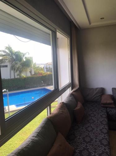 sala de estar con sofá y ventana grande en Bel Appartement à PUERTO MARINA-DAR BOUAZZA avec piscines et jardins, en Casablanca