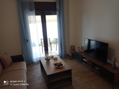 a living room with a couch and a tv at Sunset Apartment in Epanomi