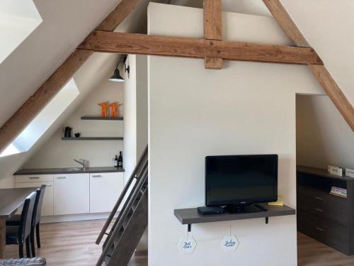 a kitchen and a living room with a tv in a attic at B&B Col del vino in Wevelgem