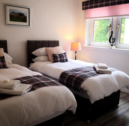 een slaapkamer met 2 bedden en een raam bij Iona in Stirling