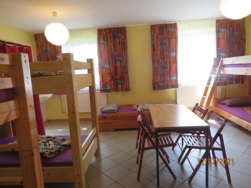 a room with bunk beds and a table and a desk at Hostel Waldhaus am Ferienpark-Mehrbett-Gruppenzimmer mit Waschbecken in Mirow