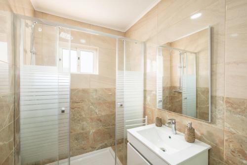 a bathroom with a shower and a sink and a mirror at Albufeira - 3 bedrooms - free wifi in Albufeira