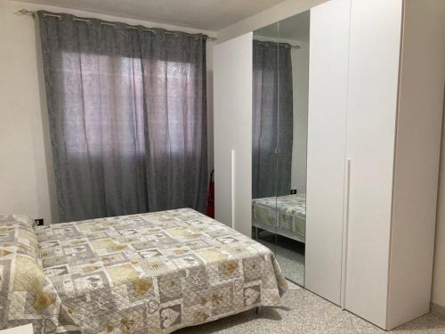 een slaapkamer met een bed, een raam en een spiegel bij Appartamento sulla piazza 90 m dal mare in Anzio