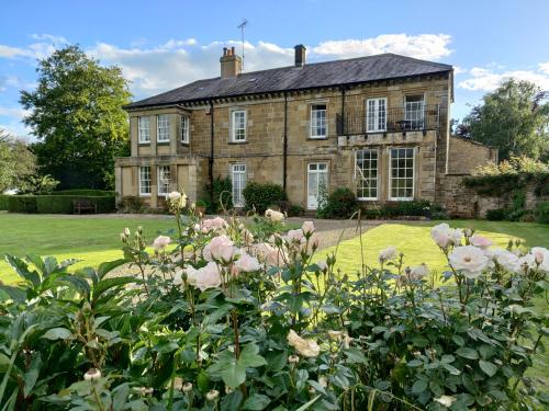 an old brick house with flowers in front of it at Sutton Hall Resort in Thirsk