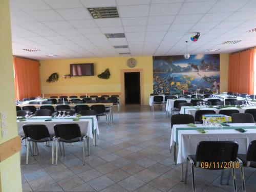 a large room with tables and chairs and a clock at Hostel Waldhaus am Ferienpark-Mehrbett-Gruppenzimmer mit Waschbecken in Mirow