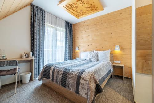 a bedroom with a bed with a wooden wall at Stachelisko - domki i pokoje in Chochołów