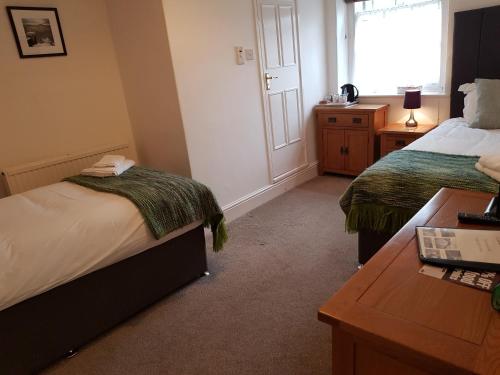 a bedroom with two beds and a desk and a window at Ty Helyg Guest House in Brecon