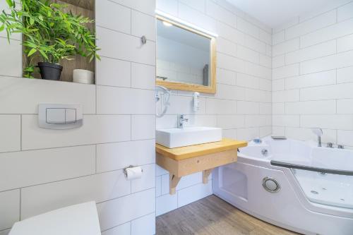 a white bathroom with a sink and a mirror at Stachelisko - domki i pokoje in Chochołów