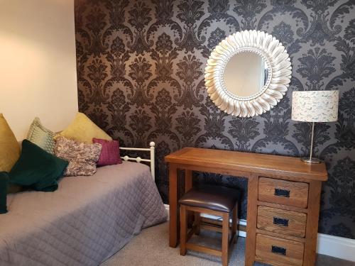 a bedroom with a bed and a table with a mirror at Ty Helyg Guest House in Brecon