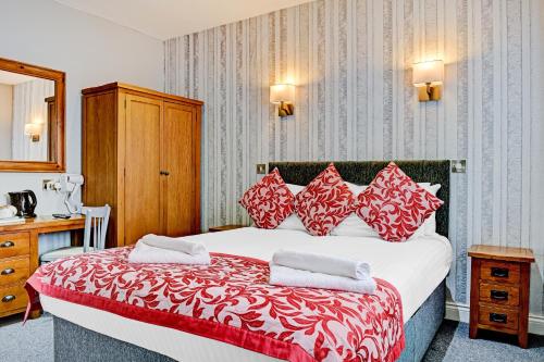 a hotel room with a large bed with red and white pillows at OYO Dovecote Hotel in Birmingham