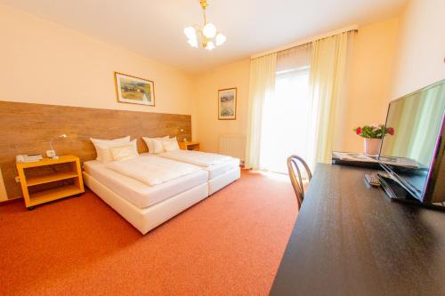 a bedroom with a bed and a television and a desk at Hotel Centro Fürth Nürnberg in Fürth