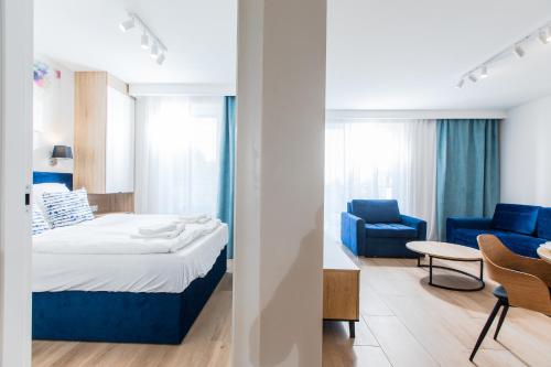 a hotel room with a bed and a blue chair at Resort Apartamenty Klifowa Rewal 54 in Rewal