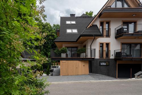 a house with a black roof and a garage at Villa 16 Zakopane in Zakopane