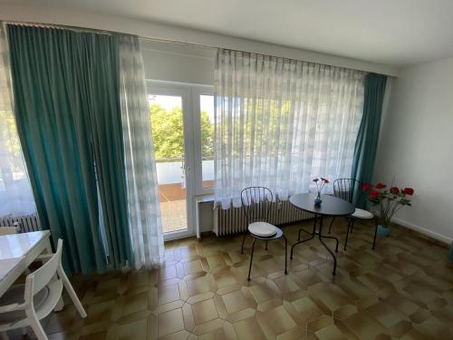 ein Wohnzimmer mit einem Tisch, Stühlen und Fenstern in der Unterkunft Ferienwohnung Südpark Apartment - Bad Nauheim in Bad Nauheim