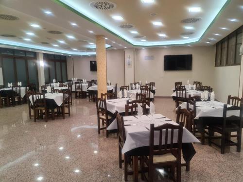 uma sala de jantar com mesas e cadeiras e uma televisão em Hotel Segontia em Épila
