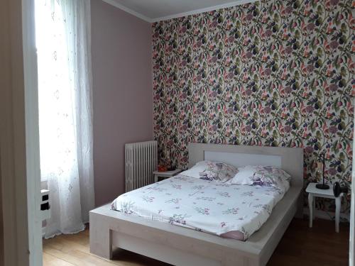 Ligueil的住宿－CHANTOISEAU，一间卧室配有一张带花卉壁纸的床