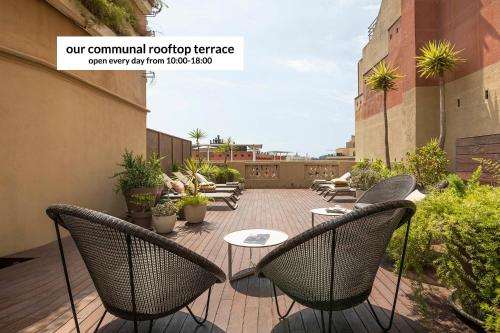un patio con sillas y mesas en un balcón en DestinationBCN Universitat Apartments, en Barcelona