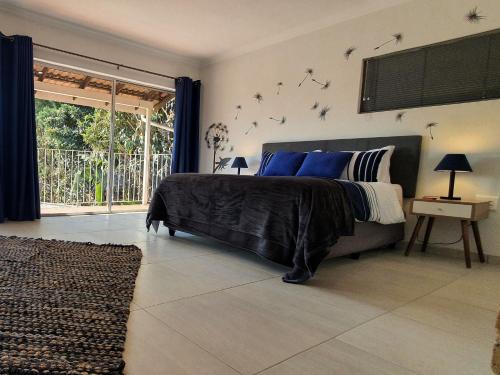 um quarto com uma cama com lençóis azuis e pássaros na parede em Wilgespruit Manor Flat em Roodepoort