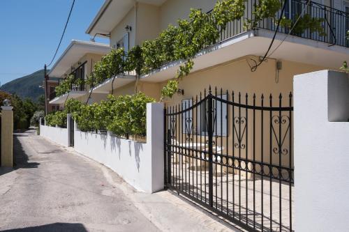 een wit hek met een zwarte poort naast een gebouw bij Soula Apartments in Ýpsos