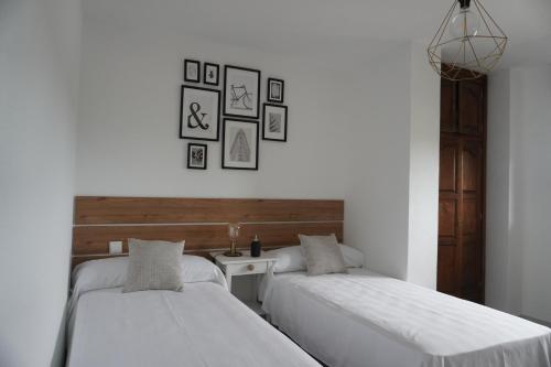 dwa łóżka w pokoju ze stołem i obrazami na ścianie w obiekcie Hostal La Biela 43 w mieście Galizano