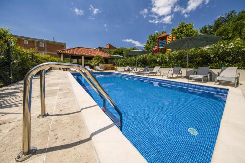 a swimming pool with chairs and an umbrella at Villa Dvori Viškovi in Podstrana