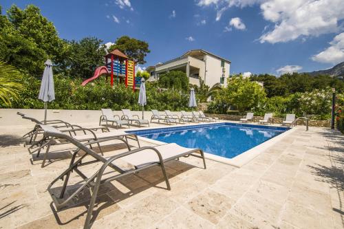 a swimming pool with lounge chairs and a slide at Villa Dvori Viškovi in Podstrana