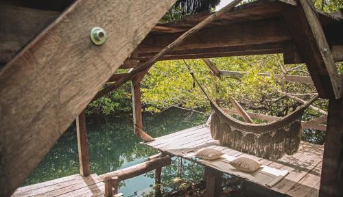 a hammock in a tree house next to a river at Uman Glamping & Cenote Tulum in Tulum