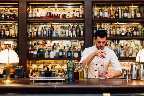 
a man sitting at a counter in a bar at Rosewood London in London
