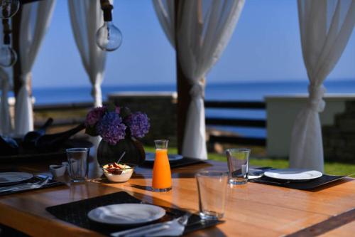a wooden table with plates and a vase of flowers on it at Toxotis Villas in Armenistis