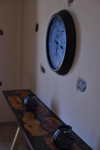a clock hanging on a wall next to a table at Toxotis Villas in Armenistis