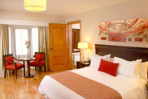 a hotel room with two beds and a television at Alma Del Lago Suites & Spa in San Carlos de Bariloche