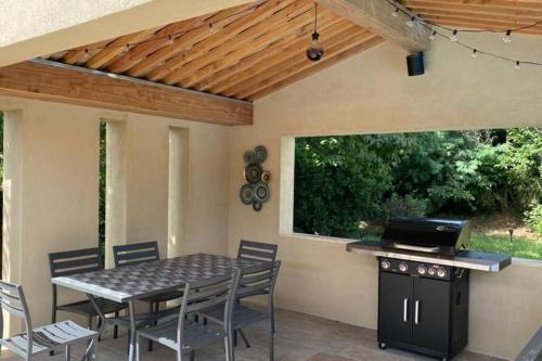 a patio with a table and chairs and a grill at Magnifique villa avec piscine au coeur des vignes in Cogolin