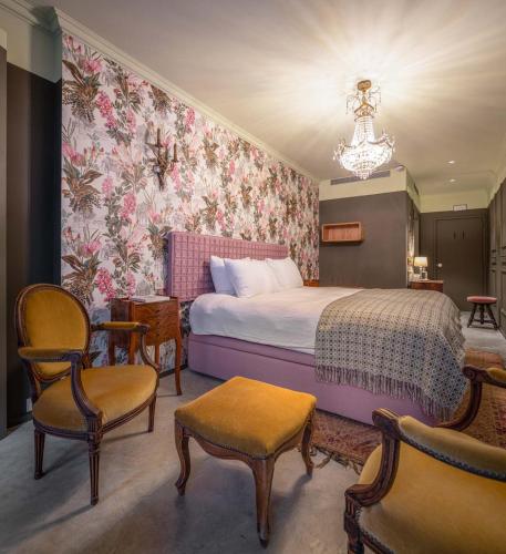 a bedroom with a bed and chairs and a chandelier at toctoctoc lisboa in Lisbon