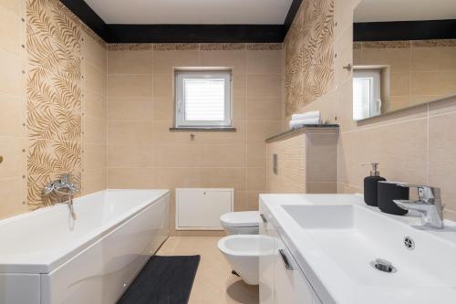 a bathroom with a tub and a toilet and a sink at Villa Vires in Labin