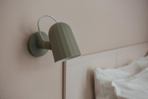 a green lamp on a wall next to a bed at Hotel Bries Den Haag - Scheveningen in The Hague