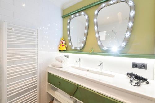 La salle de bains est pourvue d'un lavabo et de deux miroirs. dans l'établissement Plopsa Hotel, à La Panne